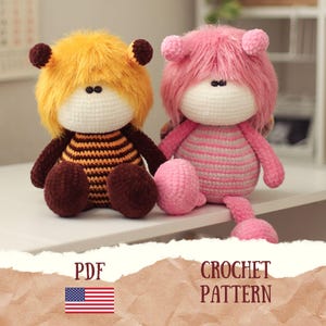 May include: Two handmade crochet dolls. One doll has yellow shaggy hair and a brown and orange striped body. The other doll has pink shaggy hair and a pink and grey striped body. The dolls are sitting on a white surface. The image includes the text "PDF" and "CROCHET PATTERN".