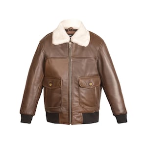 Può includere: Una giacca bomber in pelle marrone con colletto in pelliccia sintetica e chiusura a zip. La giacca ha due grandi tasche sul davanti e un elastico a costine in vita e sui polsini.