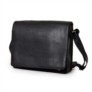 May include: A black leather messenger bag with a flap closure and adjustable shoulder strap. The bag has a rectangular shape and a textured surface. The strap is attached with gold-colored hardware.