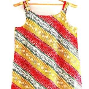 May include: A sleeveless dress with a red, yellow, and green diagonal stripe pattern. The dress has a square neckline and a simple design.