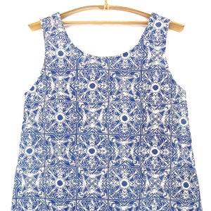 May include: A sleeveless blue and white dress with a geometric pattern. The dress has a scoop neck and a loose fit.