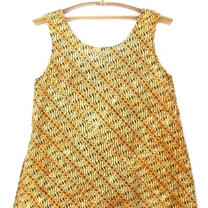 May include: A sleeveless dress with a yellow and brown geometric pattern. The dress has a scoop neck and a loose fit.