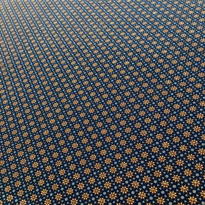 May include: Dark blue fabric with a repeating pattern of gold and white floral designs. The flowers are arranged in a grid-like pattern, creating a textured appearance. The overall effect is a rich and detailed textile.