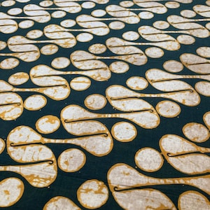 May include: Dark teal fabric with a repeating pattern of white and gold abstract shapes. The design features teardrop and circular forms connected by thin, curved lines. The fabric has a textured appearance, suggesting a natural fiber.