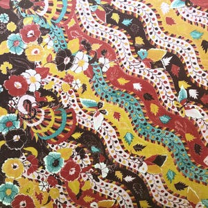 May include: A colorful textile with a repeating floral pattern. The design features wavy bands of red, yellow, and teal, interspersed with detailed floral and leaf motifs in various colors. The background is a dark brown.