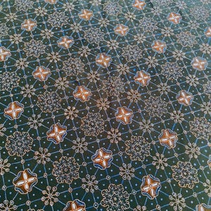 May include: A dark green fabric featuring a repeating geometric pattern of white dotted lines forming a grid. The design includes alternating floral-like motifs in shades of brown, white, and blue, interspersed with small white circular star shapes.