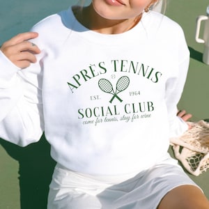May include: White sweatshirt with a green graphic design that says "APRÈS TENNIS EST. 1964 SOCIAL CLUB come for tennis, stay for wine".