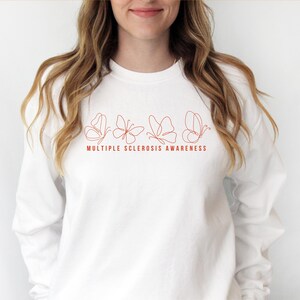 May include: White sweatshirt with a line drawing of five butterflies in orange. The text "MULTIPLE SCLEROSIS AWARENESS" is printed below the butterflies.