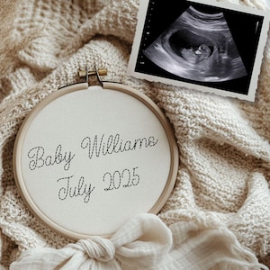 May include: A white embroidery hoop with the text "Baby Williams July 2025" stitched in black thread. A black and white ultrasound image is in the background.