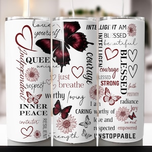 Può includere: Bicchiere bianco con un design a farfalla e floreale. Il bicchiere presenta parole ispiratrici come "Queen", "Blessed" e "Unstoppable" in un mix di caratteri e colori. Il design include cuori e farfalle.