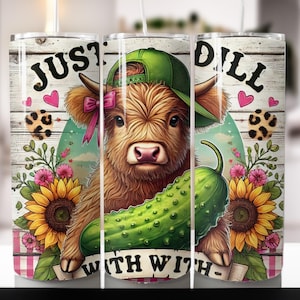 May include: A white tumbler with a brown and white cow with a green hat and a pink bow holding a green pickle. The tumbler has the text "Just Dill With" on the left and "Dill" on the right. The background is a white woodgrain pattern with pink and green flowers.