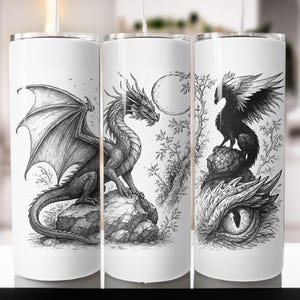May include: White tumbler featuring a detailed black and white illustration of a dragon with outstretched wings, a full moon, and a bird perched on a rock. The design is a fantasy theme.