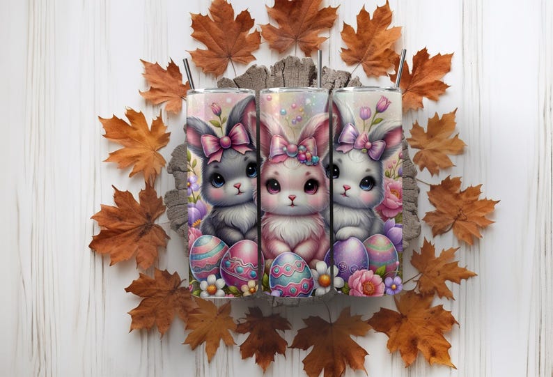 May include: Three stainless steel tumblers with a pastel pink, purple, and blue Easter bunny design. Each bunny is holding an Easter egg and surrounded by flowers.
