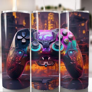 Puede incluir: Un vaso de acero inoxidable con un diseño colorido de un mando de videojuegos. El mando tiene una combinación de colores negro y morado con detalles en azul y turquesa. El fondo es un paisaje urbano borroso.