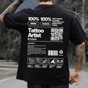 Puede incluir: Camiseta negra con un diseño gráfico blanco que dice "100% 100% Inked Chaos Tattoo Artist @custom". El gráfico también incluye un código QR, un código de barras y un símbolo de reciclaje. El texto "Won't change the world, but it damn sure makes it look badass" también está incluido en el gráfico.