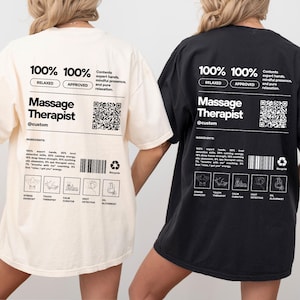 May include: Ivory and black t-shirts with the text "Massage Therapist" in a bold, modern font. The shirts feature a list of "ingredients" and a QR code. The ivory shirt has a white design, while the black shirt has a white design.