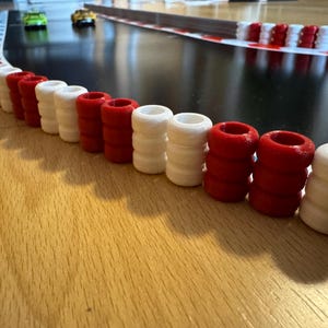 Può includere: Primo piano di una barriera per pista da corsa realizzata con cilindri di plastica rossi e bianchi alternati. La barriera è curva e si estende verso destra dell'immagine.