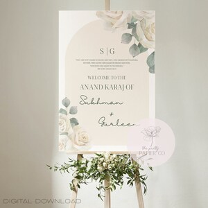 Puede incluir: Un cartel de boda con un diseño floral de acuarela en tonos verdes y blancos. El cartel dice "Bienvenido al Anand Karaj de Sukhman + Gurleen". El texto "the pretty papier co" también está incluido en el cartel.