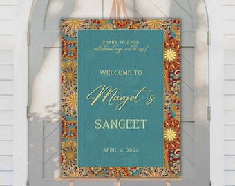 May include: A teal blue welcome sign with a gold border and intricate floral patterns. The sign reads "Thank you for celebrating with us! Welcome to Mangot's Sangeet April 4, 2024".