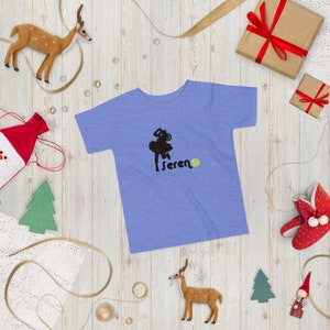 Puede incluir: Una camiseta azul claro con una silueta negra de una jugadora de tenis y la palabra "Serena" con una pelota de tenis verde.