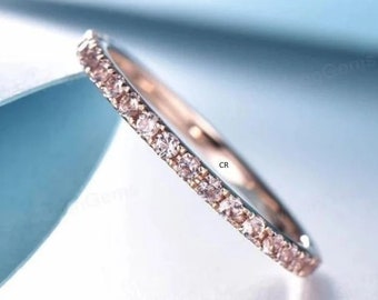 May include: A delicate rose gold band with a row of small, clear gemstones set in a pave setting.