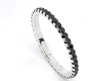 May include: A thin silver band with a row of black gemstones set in a pave setting.