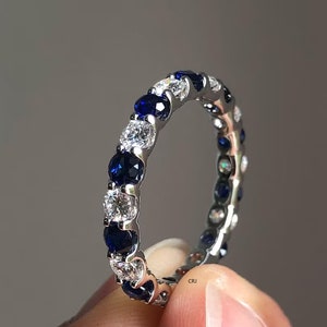 Könnte beinhalten: Ein silberner Bandring mit abwechselnden blauen Saphiren und klaren Diamanten.