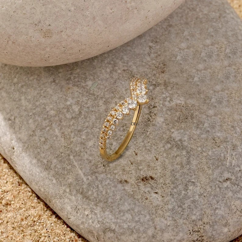 May include: A gold ring with a V-shaped design set with small clear stones.