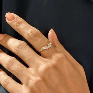 May include: A gold ring with a V-shaped design set with small clear stones.