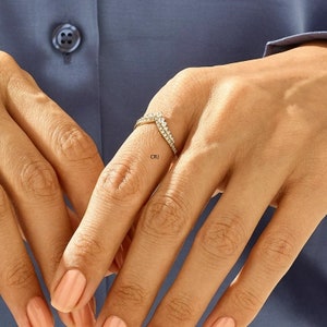 May include: A gold ring with a V-shaped design set with small clear stones.