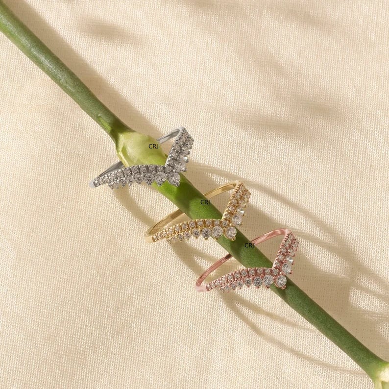 May include: Three V-shaped rings with a row of clear cubic zirconia stones on each side. The rings are in silver, gold, and rose gold.