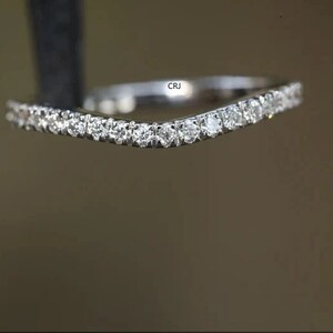 May include: A delicate, curved wedding band with a sparkling row of small diamonds.