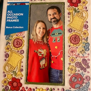 May include: Embroidered photo frame with a green border, featuring a couple in red sweaters. The frame is decorated with colorful floral and butterfly embroidery. The text on the packaging reads "ALL OCCASION PHOTO FRAMES" and "Bonus Collection".