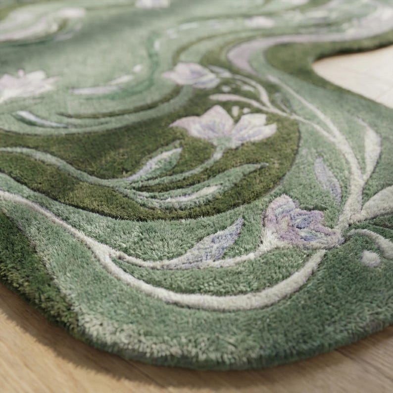 Op de afbeelding: Een groene vloerkleed met een bloemenontwerp. Het vloerkleed heeft een wervelend patroon in groentinten, met witte en lavendelkleurige bloemen en bladeren. Het vloerkleed heeft een zacht, getextureerd uiterlijk.