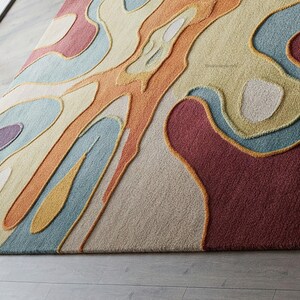 Pu&ograve; includere: Tappeto d'area astratto con un motivo a spirale colorato in tonalit&agrave; di arancione, giallo, blu, rosso e beige. Il tappeto ha una superficie testurizzata e rialzata.
