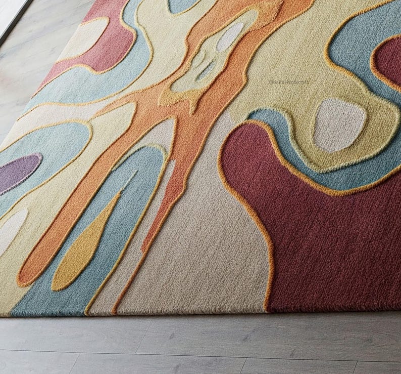 Pu&ograve; includere: Tappeto d'area astratto con un motivo a spirale colorato in tonalit&agrave; di arancione, giallo, blu, rosso e beige. Il tappeto ha una superficie testurizzata e rialzata.