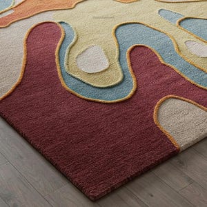 Pu&ograve; includere: Primo piano di un tappeto astratto colorato con un design testurizzato tessuto a mano. Il tappeto presenta una variet&agrave; di colori, tra cui rosso, arancione, giallo, blu e bianco. Il tappeto &egrave; fatto di lana e ha una sensazione morbida e soffice.