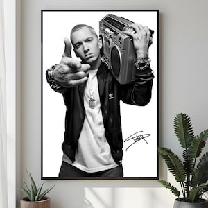 Puede incluir: Impresión enmarcada en blanco y negro de un hombre con chaqueta negra y camiseta blanca, sosteniendo una radio plateada. El hombre apunta con el dedo. La impresión incluye una firma.