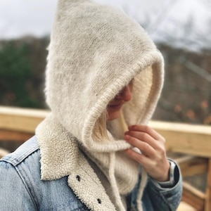 May include: A white hooded scarf with a soft, fuzzy texture. The scarf is worn over a denim jacket with a sherpa lining.