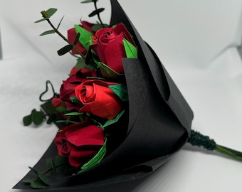 Könnte beinhalten: Ein Strauß roter Origami-Rosen, verpackt in schwarzem Papier mit grünen Blättern.
