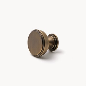May include: A round, antique brass cabinet knob with a fluted design.