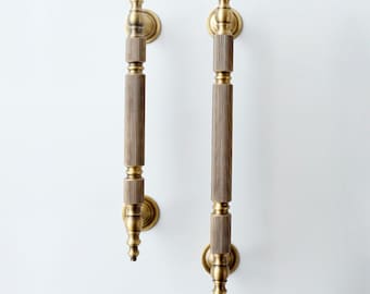 May include: Two antique brass door pulls with a fluted design. The pulls are mounted on a white wall.