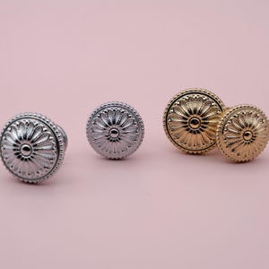 May include: Three decorative cabinet knobs with a floral design. The knobs are in silver and gold finishes.