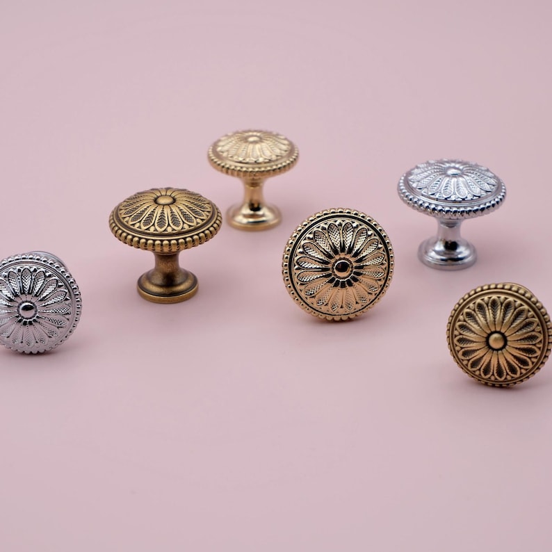 May include: Six ornate cabinet knobs in various finishes, including gold, silver, and brass. Each knob features a detailed floral design.