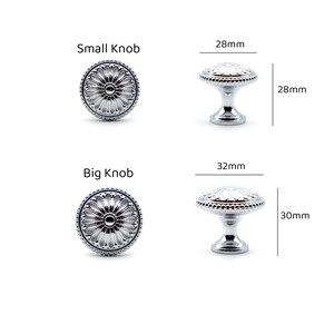 May include: Two silver decorative knobs with a floral design. The smaller knob measures 28 mm in diameter and 28 mm in height. The larger knob measures 32 mm in diameter and 30 mm in height.