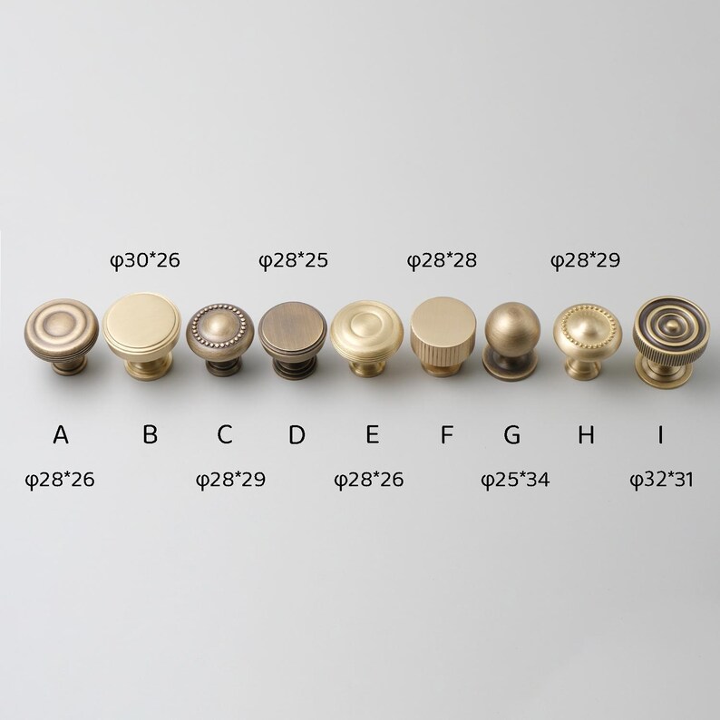 May include: Nine different styles of brass cabinet knobs in various sizes and designs. The knobs are arranged in a row from left to right, with the measurements of each knob listed below it. The measurements are in inches.
