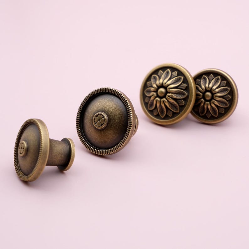 Puede incluir: Pomos de armario de lat&oacute;n antiguo con dise&ntilde;os florales y circulares. Los pomos tienen una est&eacute;tica vintage, con un acabado de lat&oacute;n oscuro y detalles intrincados. Probablemente sean para muebles o armarios.
