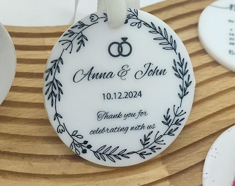 Könnte beinhalten: Runder weißer Hochzeitsschmuck mit schwarzem Blumenrand, zwei ineinander verschlungenen Ringen und dem Text "Anna & John 10.12.2024 Vielen Dank, dass Sie mit uns feiern".