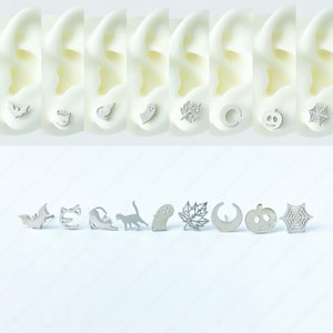 Puede incluir: Un conjunto de 10 pendientes de plata con temática de Halloween. Los pendientes presentan una variedad de diseños, que incluyen un murciélago, un gato, un fantasma, una hoja, una luna creciente, una calabaza y una telaraña.