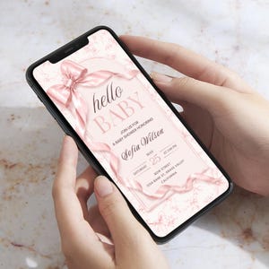 Pu&ograve; includere: Uno smartphone mostra un invito a un baby shower. L'invito presenta un nastro rosa e il testo "hello BABY". L'invito fornisce i dettagli dell'evento, incluso il nome "Sofia Wilson".